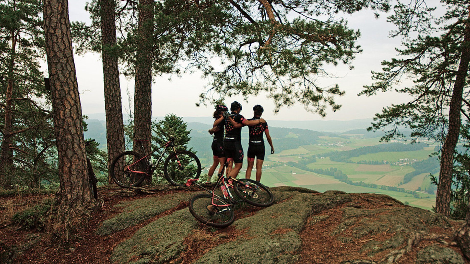 Foto: Oberösterreich Tourismus GmbH: Mountainbiken im Mühlviertel Auf diesem Bild sieht man die 3 Bikerinnen von Kette Links. Sie umarmen sich nach einer gelungenen Mountainbike-Tour und genießen den Weitblick in die Mühlviertler Landschaft.