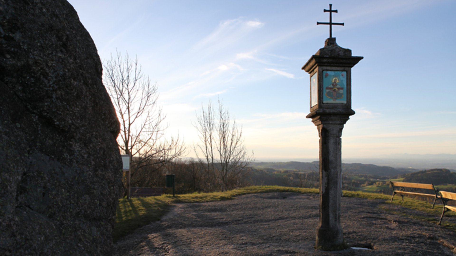 Foto: Gemeinde St. Thomas am Blasenstein: Blucklwehluckn im Mühlviertel Das Bild zeigt ein Denkmal neben einem großen Granitfelsen. Im Hintergrund sieht hat man einen Weitblick über das Mühlviertel.